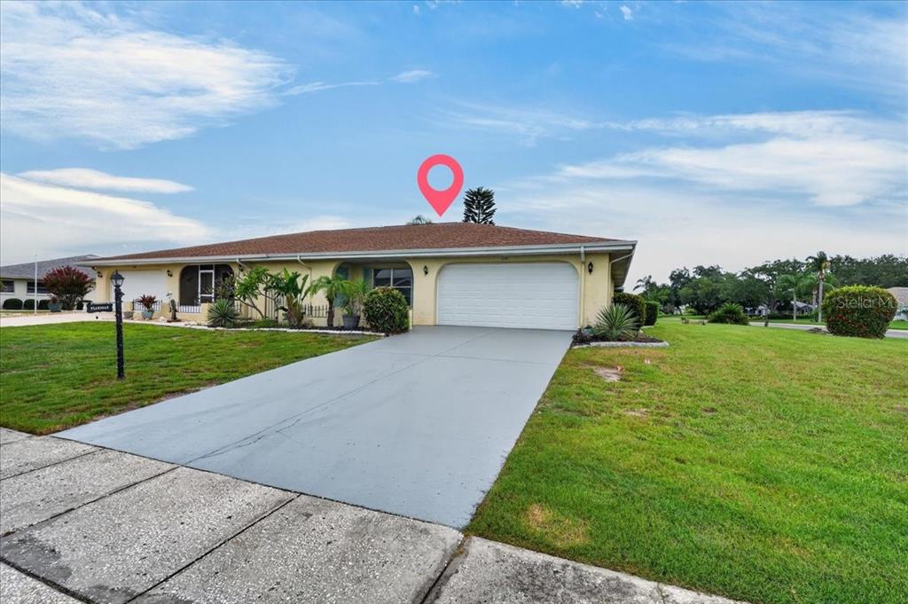A single-story house with a yellow exterior, a two-car garage, and a gray driveway — 1201 WILD FEATHER LANE, SUN CITY CENTER, FL