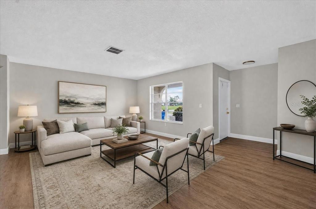 A living room features a sectional sofa, two armchairs, a coffee table, and wood-look flooring — 1201 WILD FEATHER LANE, SUN CITY CENTER, FL