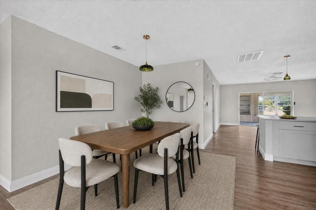A dining room features a wooden table, six chairs, a round mirror, and pendant lighting — 1201 WILD FEATHER LANE, SUN CITY CENTER, FL