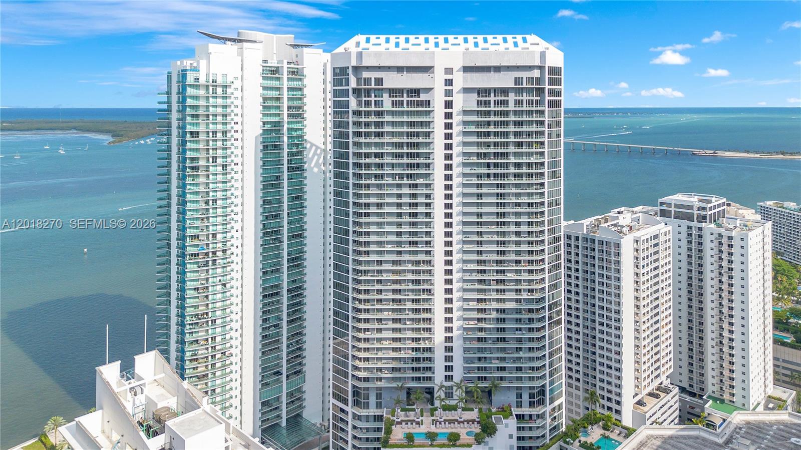 An aerial view shows three tall white residential towers situated along a waterfront — 1300 Brickell Bay Dr # 2000, Miami FL 33131, MIAMI, FL