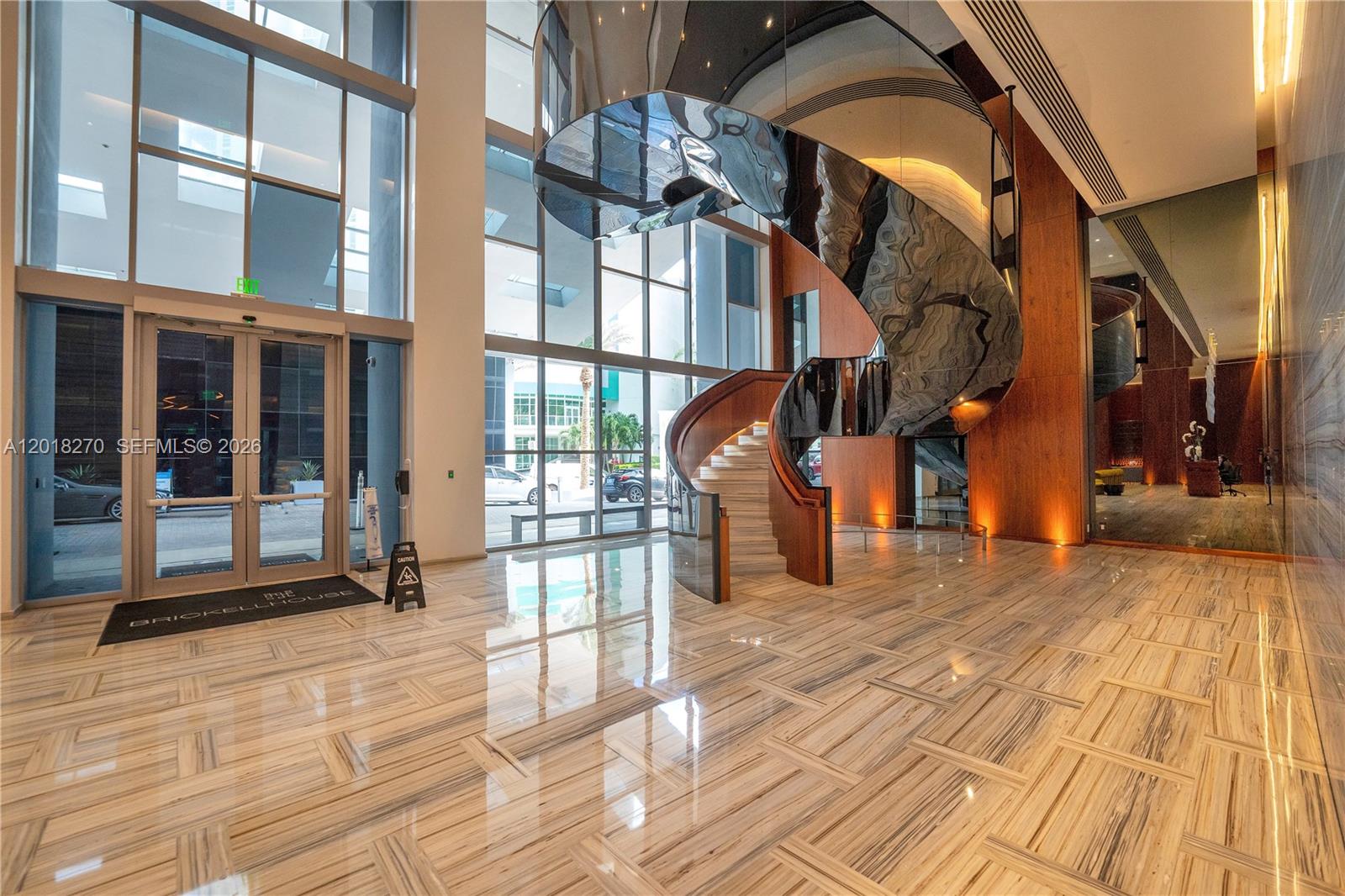 A modern building lobby features a polished marble floor and a large, sculptural spiral staircase — 1300 Brickell Bay Dr # 2000, Miami FL 33131, MIAMI, FL