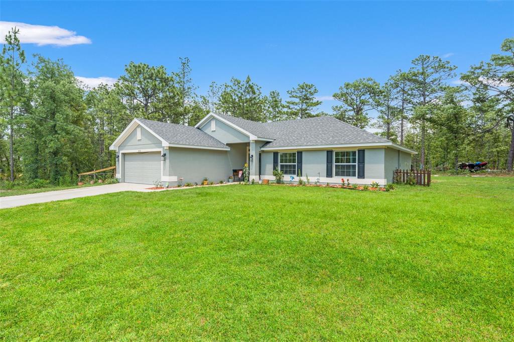 A single-story house with a gray exterior, a two-car garage, and a large front lawn — 18336 MACEK ROAD, WEEKI WACHEE, FL
