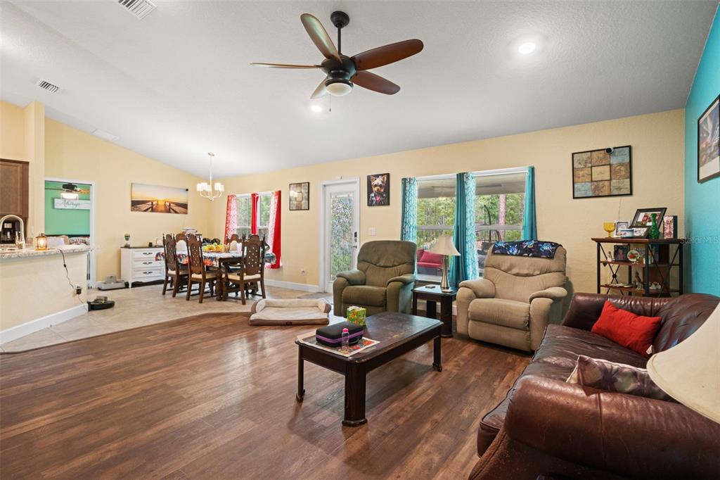 A living room with wood-look flooring, a ceiling fan, and an adjacent dining area — 18336 MACEK ROAD, WEEKI WACHEE, FL