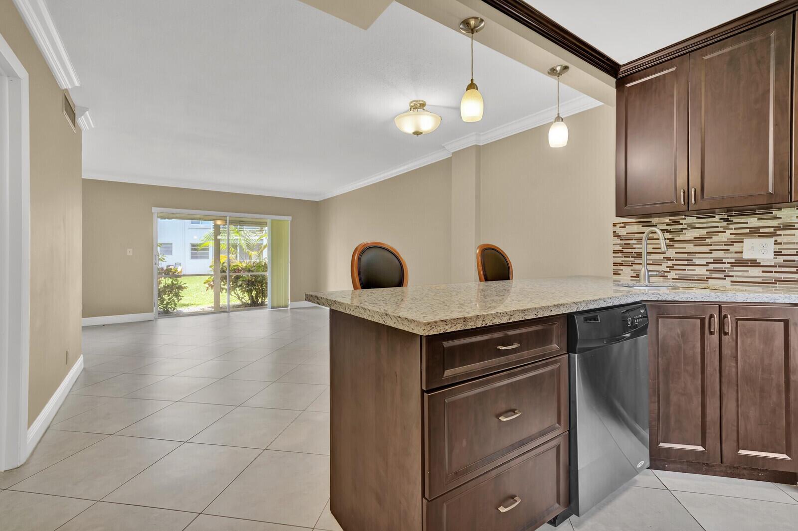 A ground-level view of a white apartment building exterior with a grassy lawn — 5501 NW 2nd Avenue # 111, Boca Raton FL 33487, BOCA RATON, FL