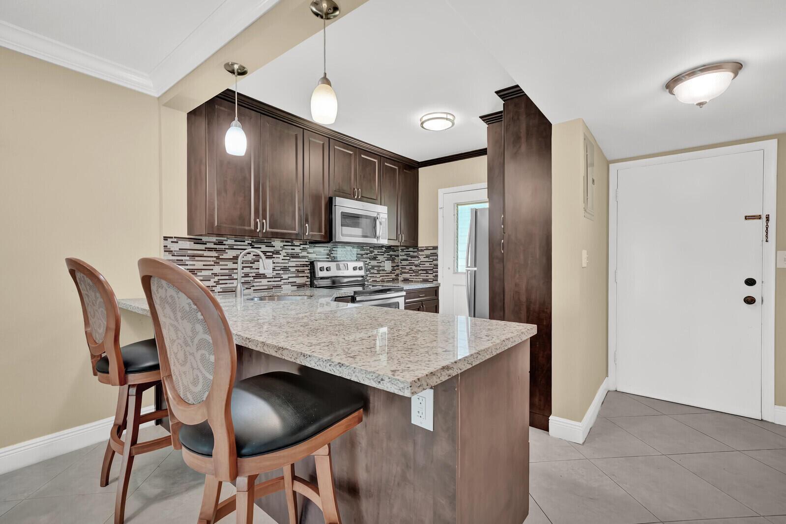 An empty living room features beige walls, white crown molding, and light-colored tile flooring — 5501 NW 2nd Avenue # 111, Boca Raton FL 33487, BOCA RATON, FL