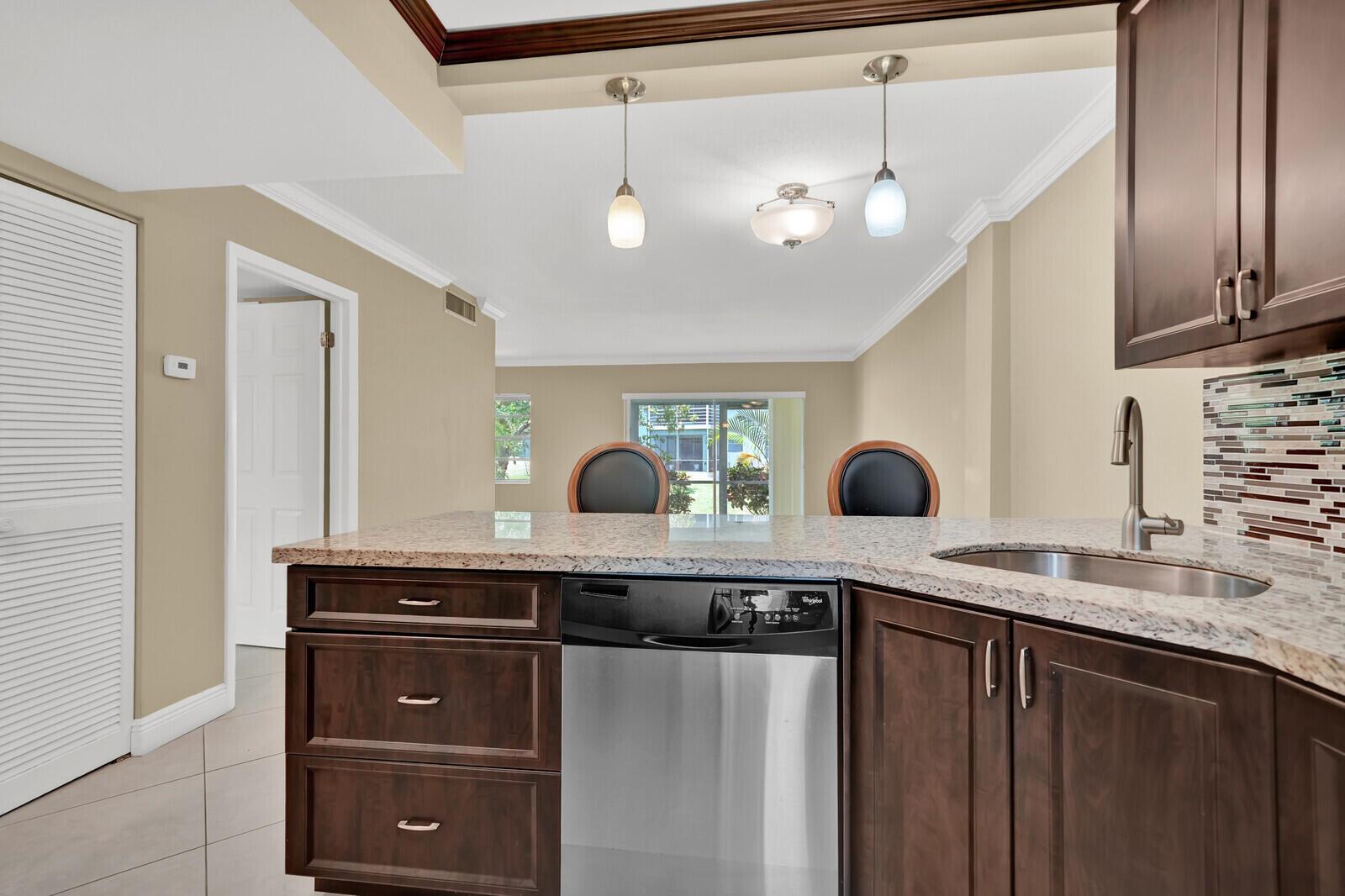 An empty room with beige walls, tile flooring, crown molding, and a sliding glass door — 5501 NW 2nd Avenue # 111, Boca Raton FL 33487, BOCA RATON, FL