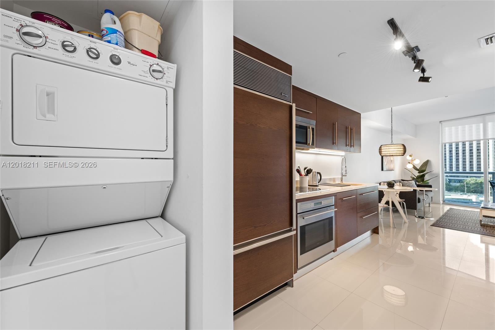 A stacked laundry unit sits beside a modern kitchen with dark wood cabinetry and appliances — 465 Brickell Ave # 904, Miami FL 33131, MIAMI, FL