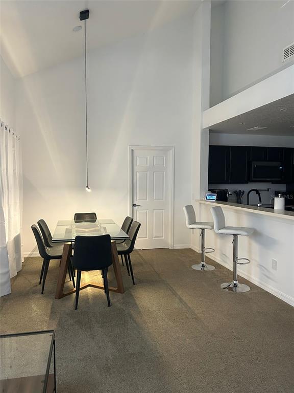 A dining area with a glass table and black chairs sits beside a kitchen counter — 970 N SPRING GARDEN AVENUE UNIT 621, DELAND, FL