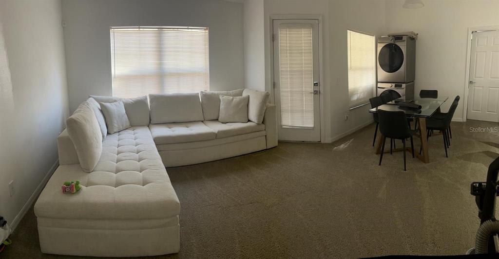 A living room features a large white sectional sofa, beige carpeting, and a dining area — 970 N SPRING GARDEN AVENUE UNIT 621, DELAND, FL