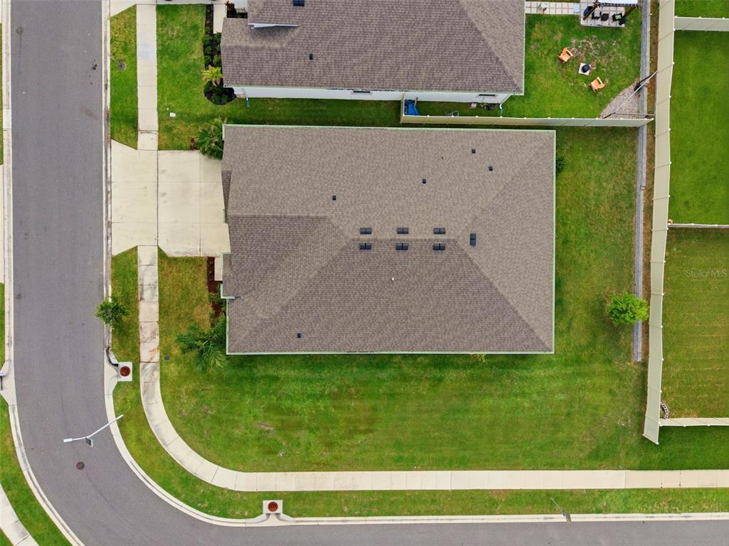 An aerial view shows a single-family home with a shingled roof and a fenced yard — 32337 CONCHSHELL SAIL STREET, WESLEY CHAPEL, FL