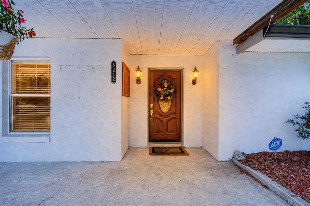 A front entryway features a wooden door with a wreath, two wall sconces, and stucco walls — 5242 COUNTY LINE ROAD, LAKELAND, FL