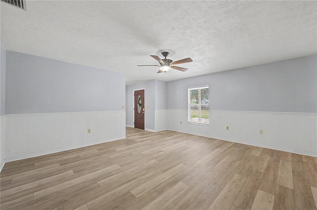 A living room features light gray walls, white wainscoting, wood-look flooring, and a ceiling fan — 5242 COUNTY LINE ROAD, LAKELAND, FL