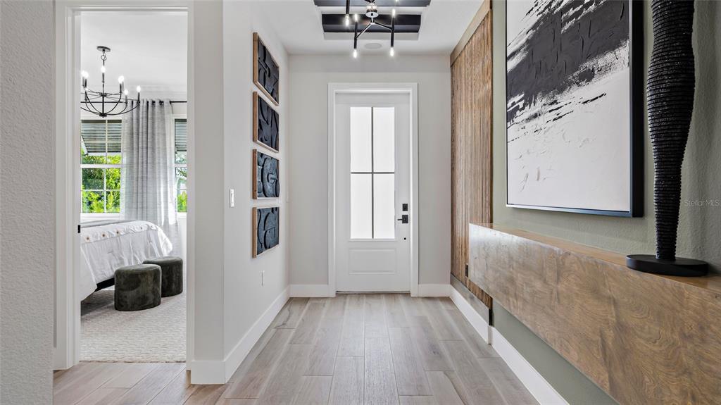 A modern entryway features wood-look tile flooring, a white front door, and a floating wood console — 1736 POINT GRACE ROAD, TAVARES, FL