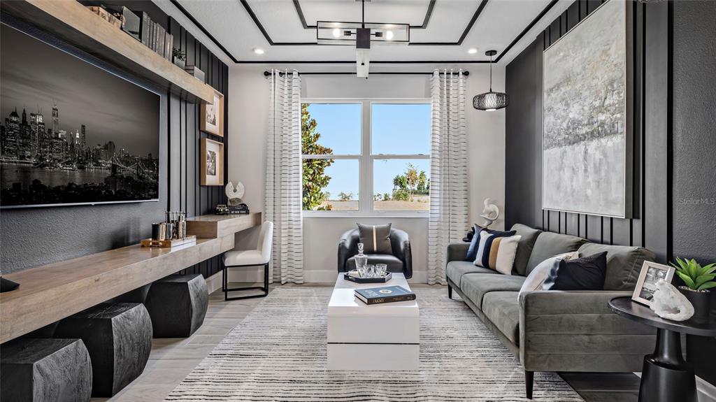 A modern living room features dark paneled walls, a floating wood desk, and a gray sofa — 1736 POINT GRACE ROAD, TAVARES, FL