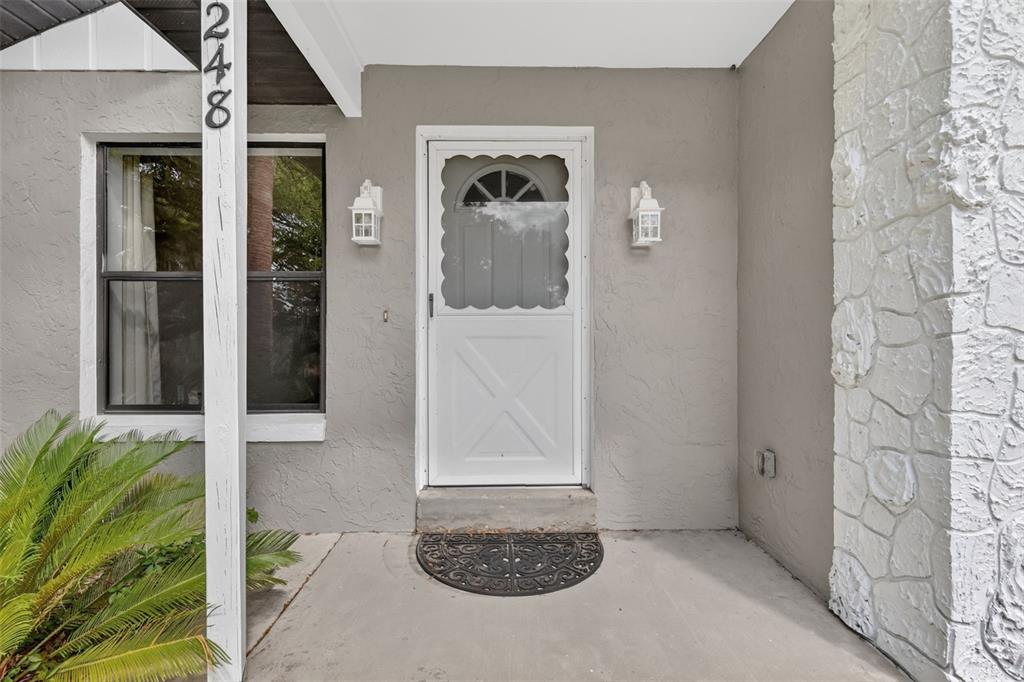 A front entryway features a white storm door, a window, and a stone-textured pillar — 40248 ORANGE CIRCLE, LADY LAKE, FL