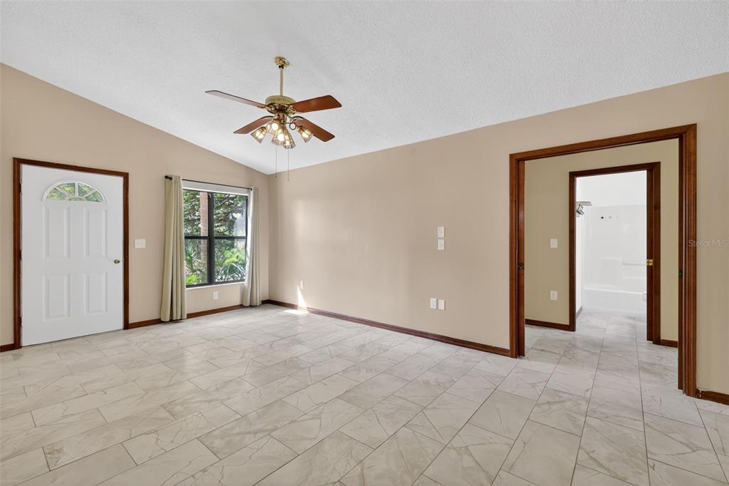 A room with light-colored tile flooring, beige walls, a ceiling fan, and a doorway — 40248 ORANGE CIRCLE, LADY LAKE, FL