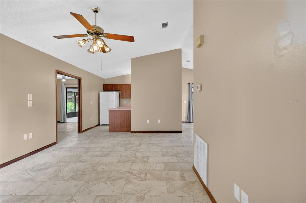 An open-concept living area with tile flooring, a ceiling fan, and a kitchen in back — 40248 ORANGE CIRCLE, LADY LAKE, FL