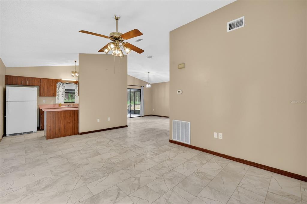 A living area with tile floors, a ceiling fan, and an adjacent kitchen with cabinets — 40248 ORANGE CIRCLE, LADY LAKE, FL
