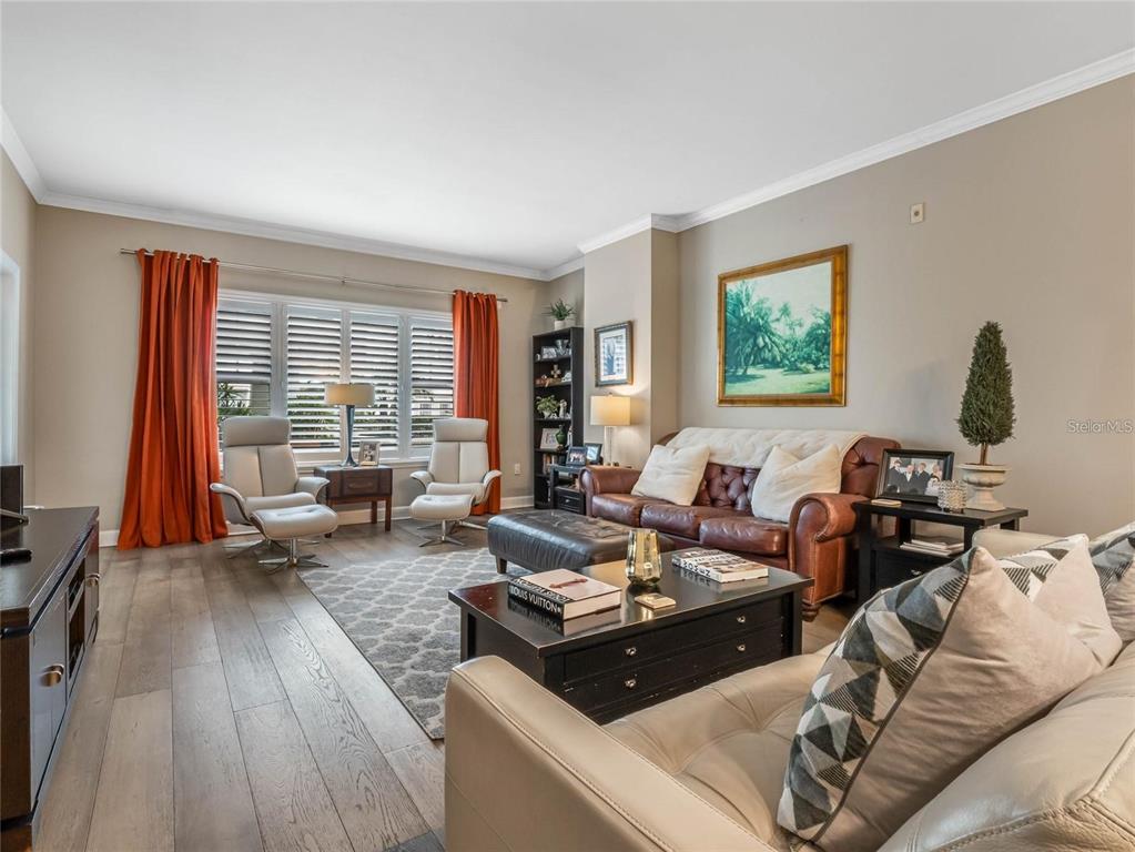 A living room features a brown leather sofa, two armchairs, and wood-look flooring — 630 VASSAR STREET UNIT 2205, ORLANDO, FL