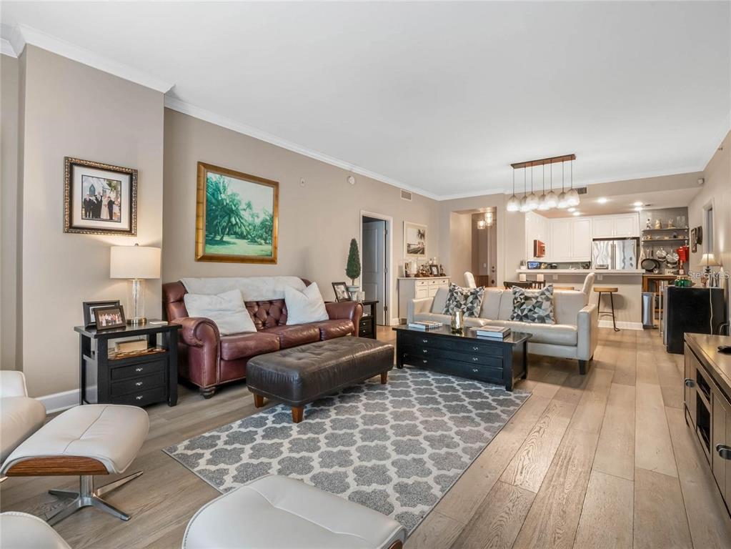 A living room features wood-look flooring, a leather sofa, a light-colored sofa, and an open kitchen — 630 VASSAR STREET UNIT 2205, ORLANDO, FL