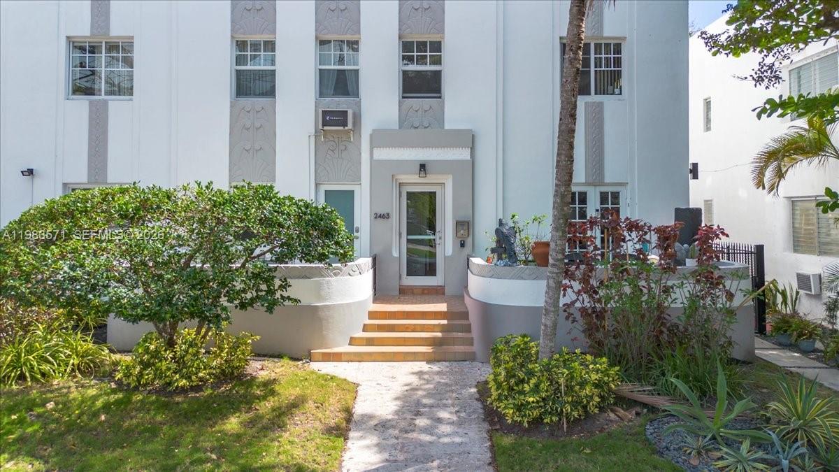 The exterior of a white multi-story building features a central entrance with steps and landscaping — 2463 Pine Tree Dr PH, Miami Beach FL 33140, MIAMI BEACH, FL