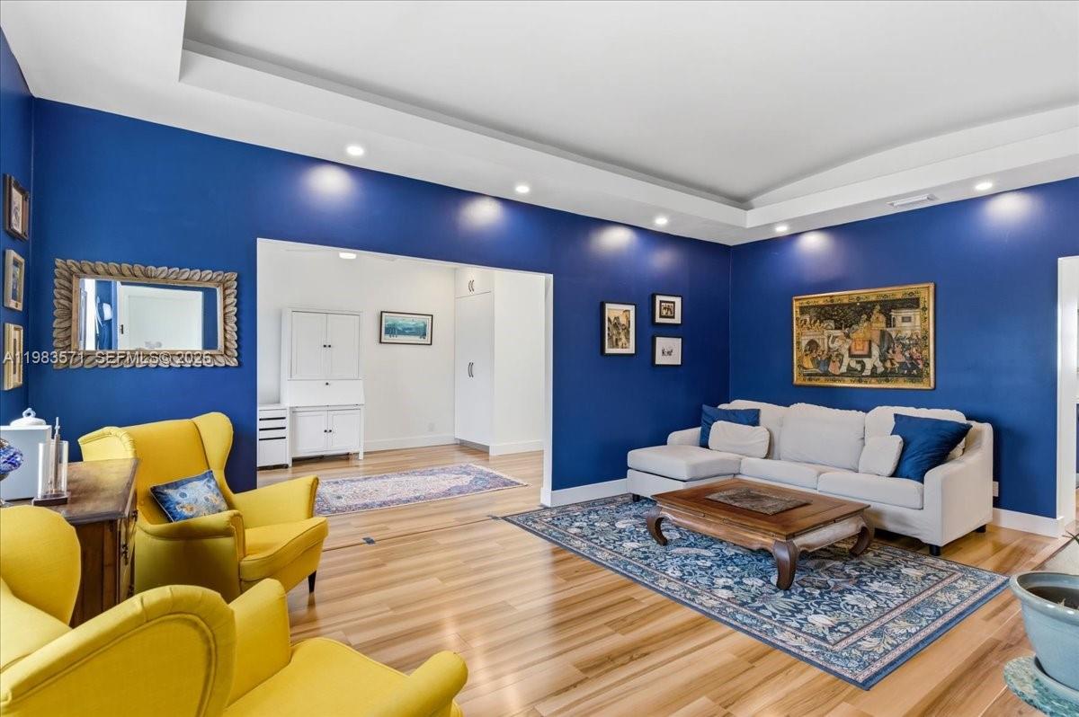 A living room features deep blue walls, a white sofa, and two yellow armchairs — 2463 Pine Tree Dr PH, Miami Beach FL 33140, MIAMI BEACH, FL