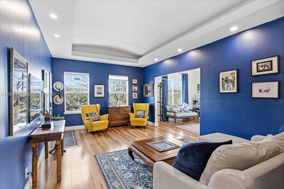 A living room with blue walls, yellow armchairs, a white sofa, and wood flooring — 2463 Pine Tree Dr PH, Miami Beach FL 33140, MIAMI BEACH, FL