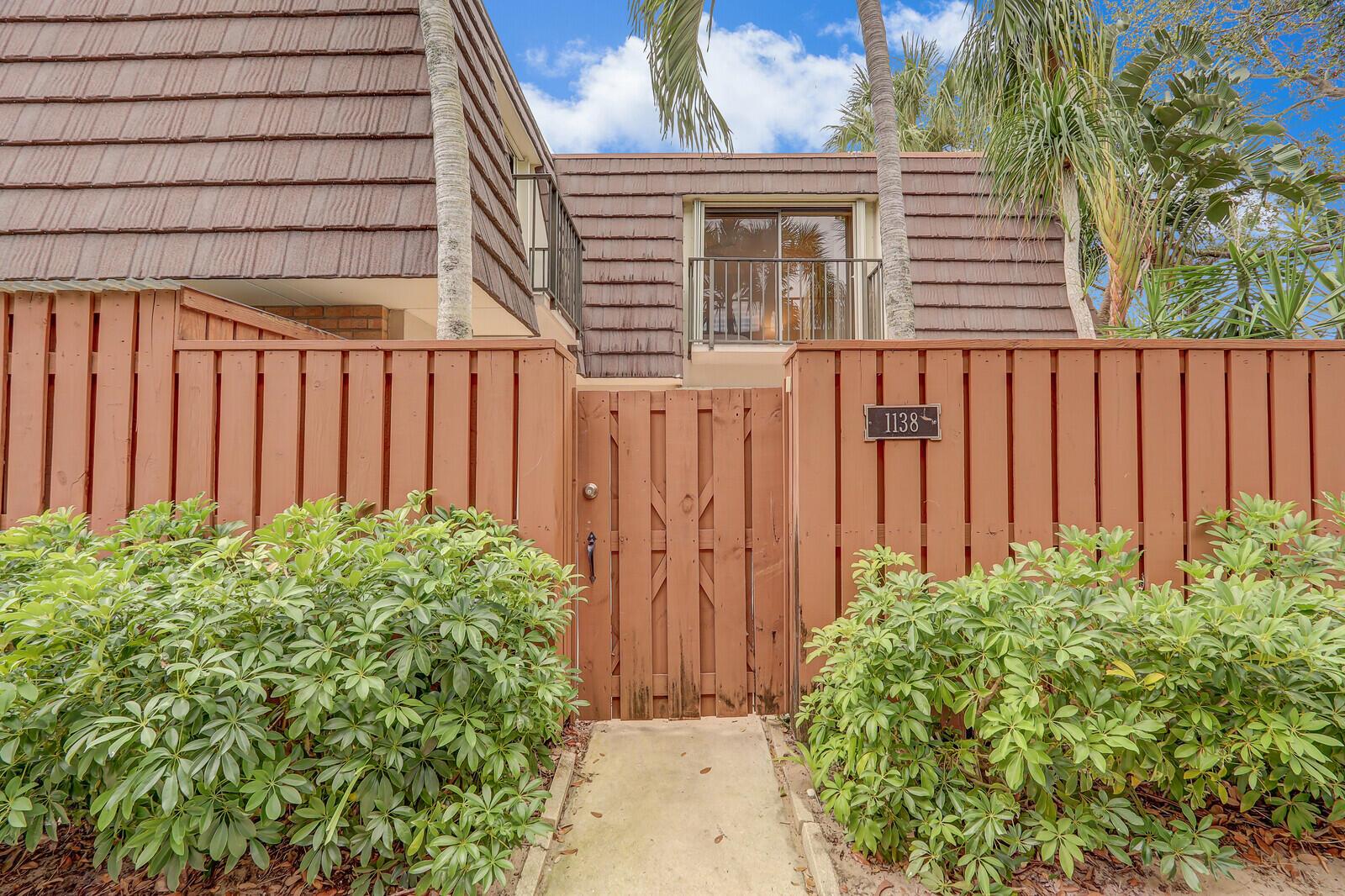 A wooden gate and fence lead to the entrance of a two-story townhouse — 1138 11th Court, Jupiter FL 33477, JUPITER, FL