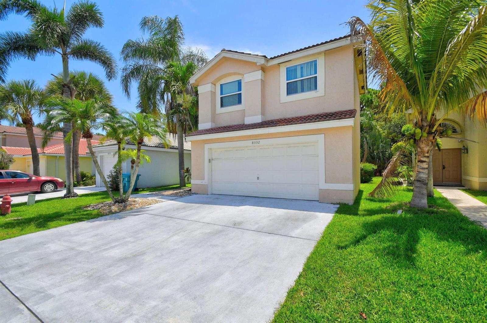 A two-story tan house with a white garage door and palm trees in the yard — 8332 Bermuda Sound Way, Boynton Beach FL 33436, BOYNTON BEACH, FL