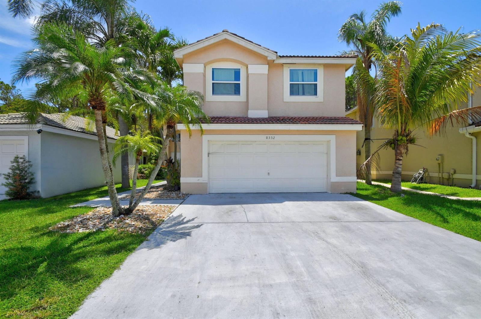 A two-story house with a beige stucco exterior, a two-car garage, and palm trees — 8332 Bermuda Sound Way, Boynton Beach FL 33436, BOYNTON BEACH, FL