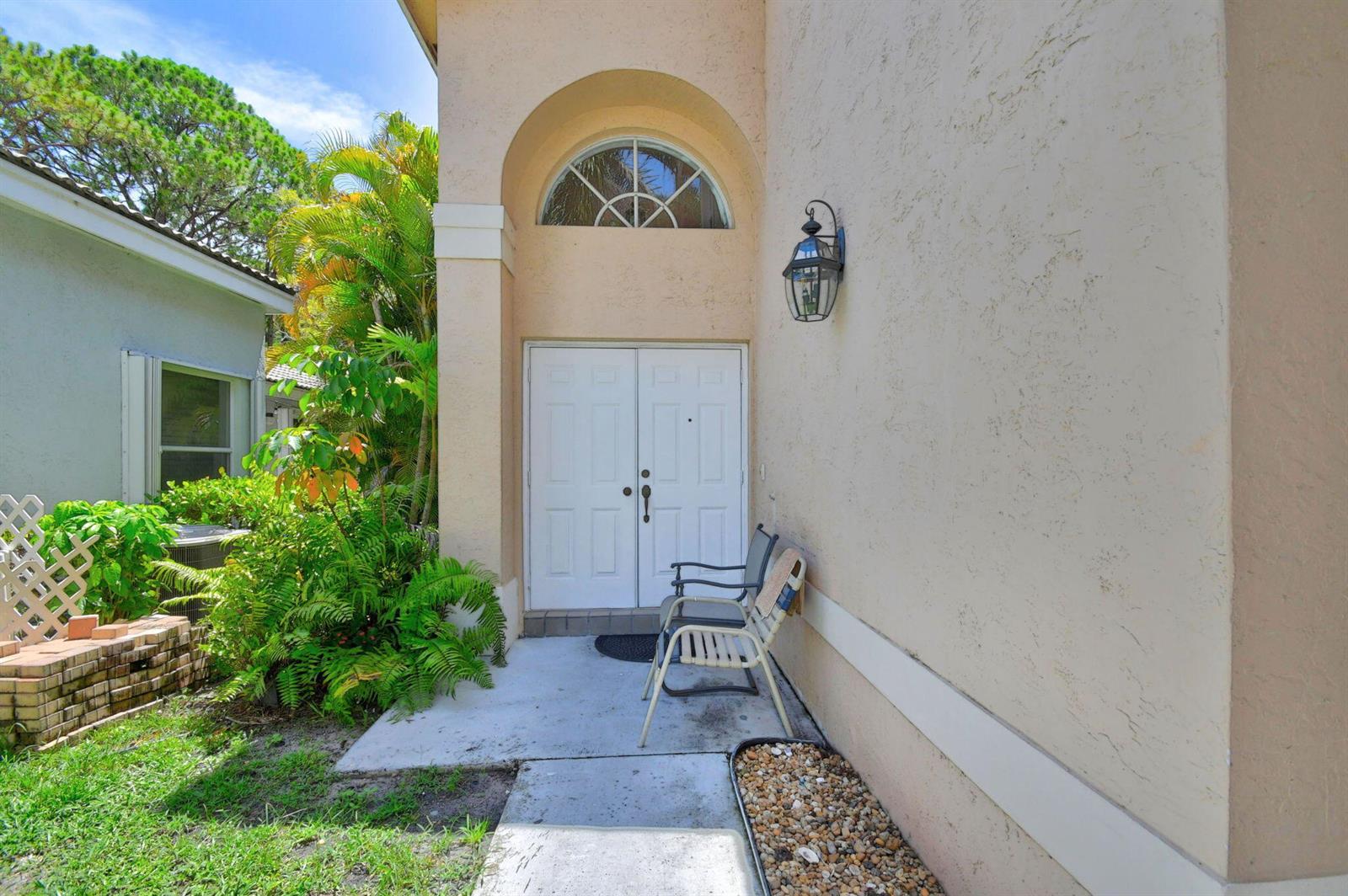 The exterior entrance features double white doors, an arched window, and two chairs on concrete — 8332 Bermuda Sound Way, Boynton Beach FL 33436, BOYNTON BEACH, FL