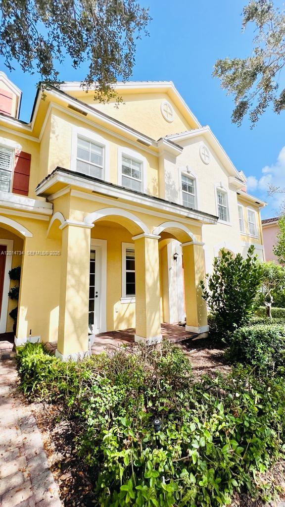 A yellow two-story townhouse features a covered front porch with white columns and landscaping — 753 DAKOTA DR # 753, Jupiter FL 33458, JUPITER, FL