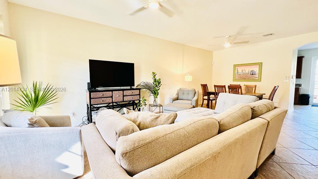 A living room features a large sectional sofa, a television on a console, and dining furniture — 753 DAKOTA DR # 753, Jupiter FL 33458, JUPITER, FL