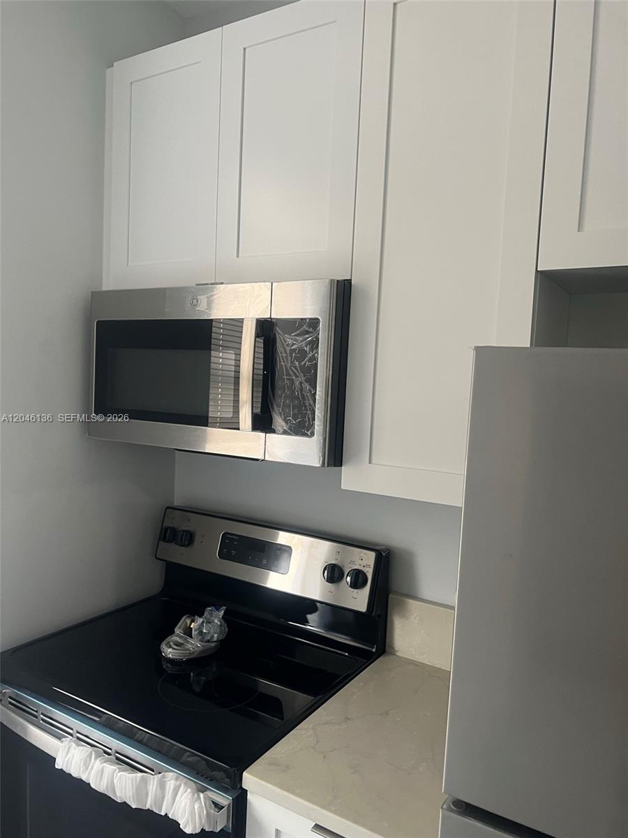 A kitchen features white shaker cabinets, a stainless steel microwave, and a black electric stove — 1450 SW 4th St # 3, Miami FL 33135, MIAMI, FL