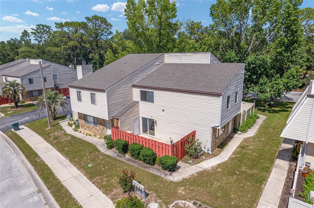 An aerial view shows a two-story townhouse with beige siding, a red fence, and landscaping — 2213 NE 45TH AVENUE, OCALA, FL