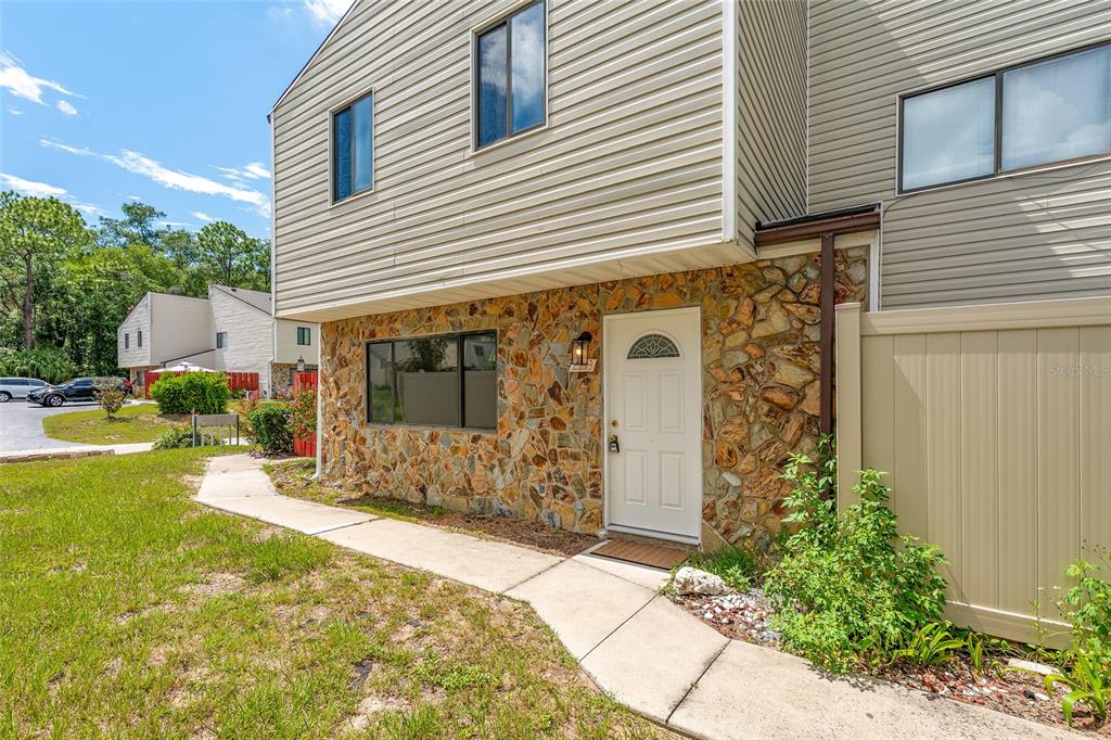 A two-story townhouse exterior features tan siding, a stone facade, and a white front door — 2213 NE 45TH AVENUE, OCALA, FL