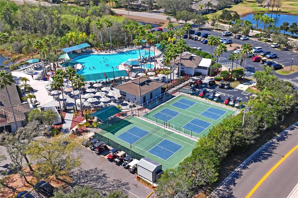 An aerial view shows a swimming pool, tennis courts, and a parking lot with golf carts — 2208 WORTHINGTON GREENS DRIVE UNIT 2208, SUN CITY CENTER, FL