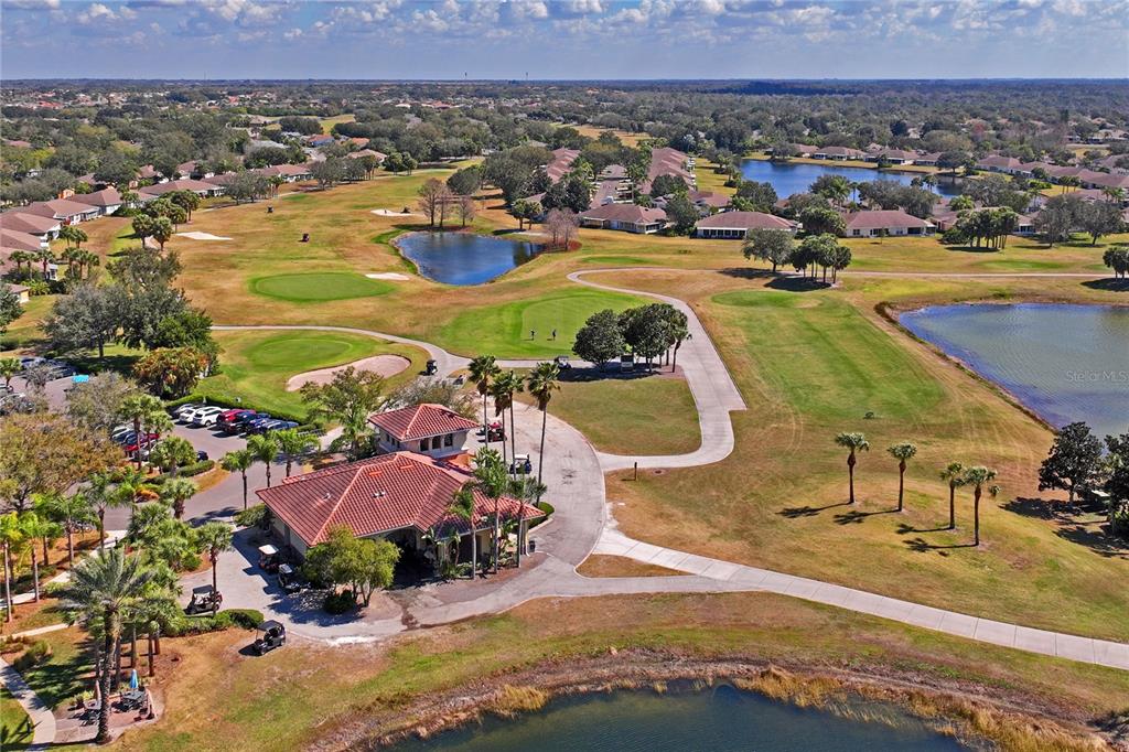 An aerial view shows a clubhouse building surrounded by a golf course and ponds — 2208 WORTHINGTON GREENS DRIVE UNIT 2208, SUN CITY CENTER, FL