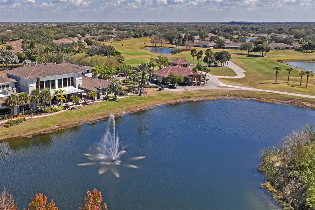 An aerial view shows a clubhouse with a fountain in a lake and golf course — 2208 WORTHINGTON GREENS DRIVE UNIT 2208, SUN CITY CENTER, FL