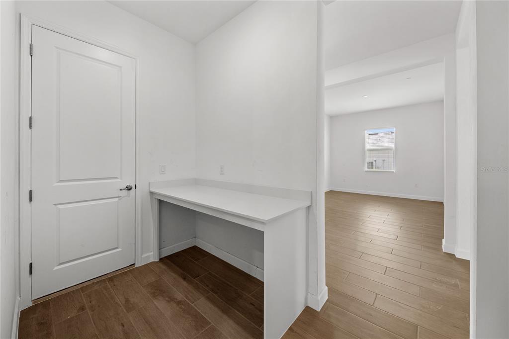 A white built-in desk sits next to a closed door in a room with wood-look flooring — 6020 MOUND KEY RUN, LAKEWOOD RANCH, FL