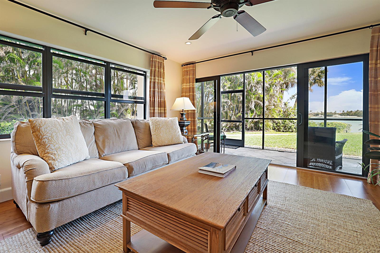 A living room features a beige sofa, wooden coffee table, and sliding glass doors to a patio — 300 Intracoastal Place # 101, Jupiter FL 33469, JUPITER, FL