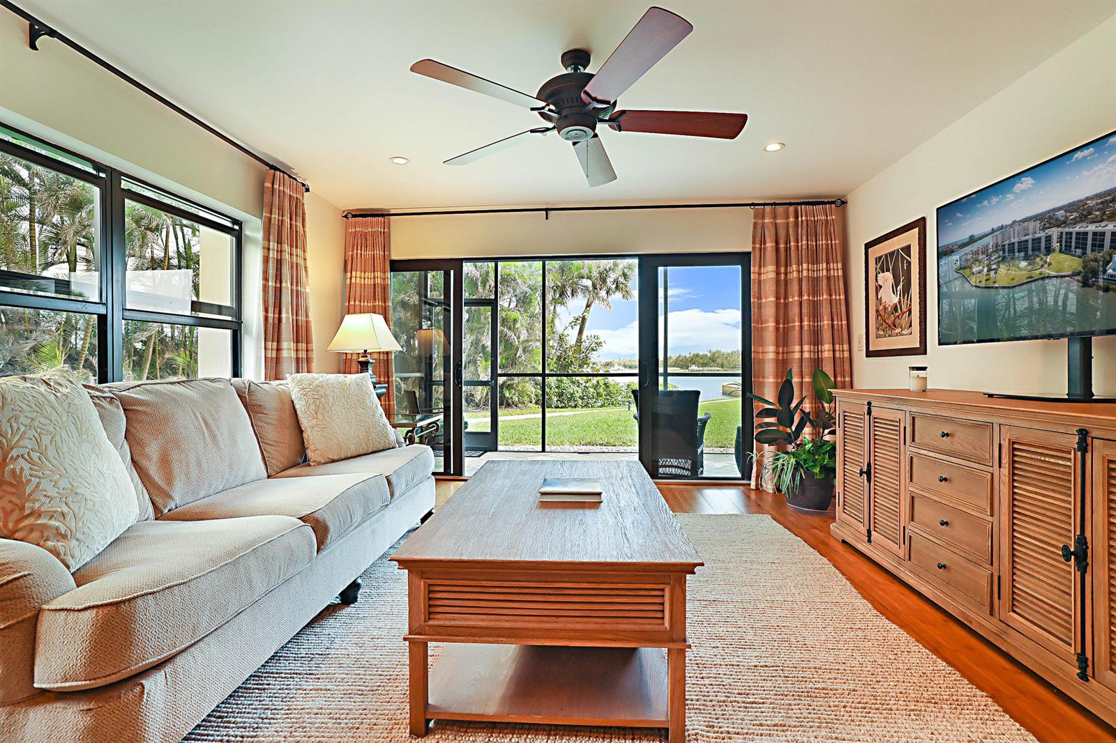 A living room features a beige sofa, wooden coffee table, media console, and sliding glass doors — 300 Intracoastal Place # 101, Jupiter FL 33469, JUPITER, FL