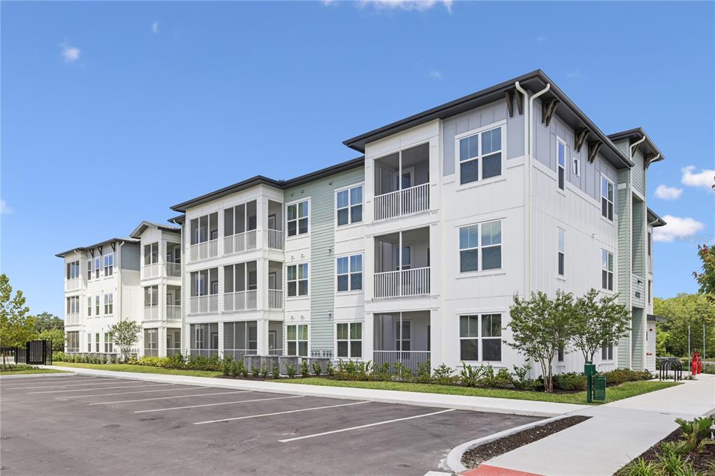 A multi-story apartment building with screened balconies and a paved parking lot in front — 4005 BISMARK DRIVE UNIT C1, KISSIMMEE, FL
