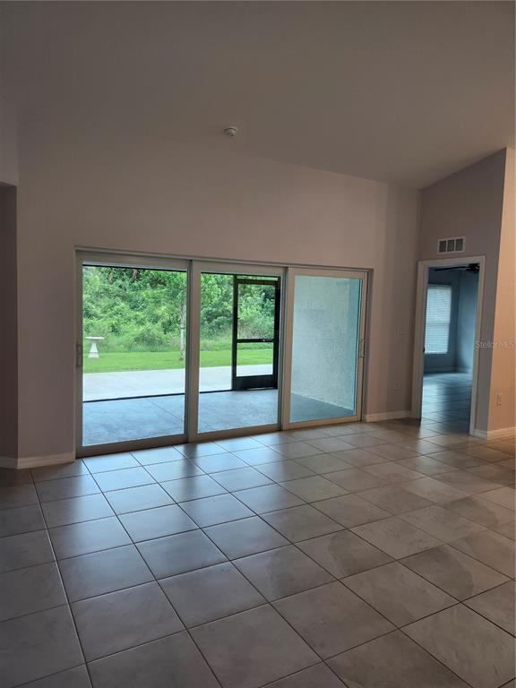 A living room with large sliding glass doors, tile flooring, and a view of a patio — 27270 PUNO DRIVE, PUNTA GORDA, FL