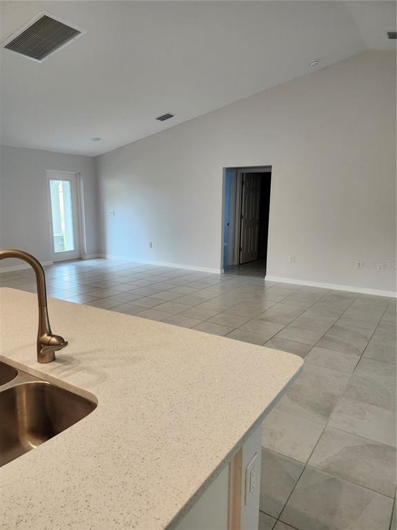 A kitchen island with a sink overlooks an open-concept living area with tiled floors — 27270 PUNO DRIVE, PUNTA GORDA, FL