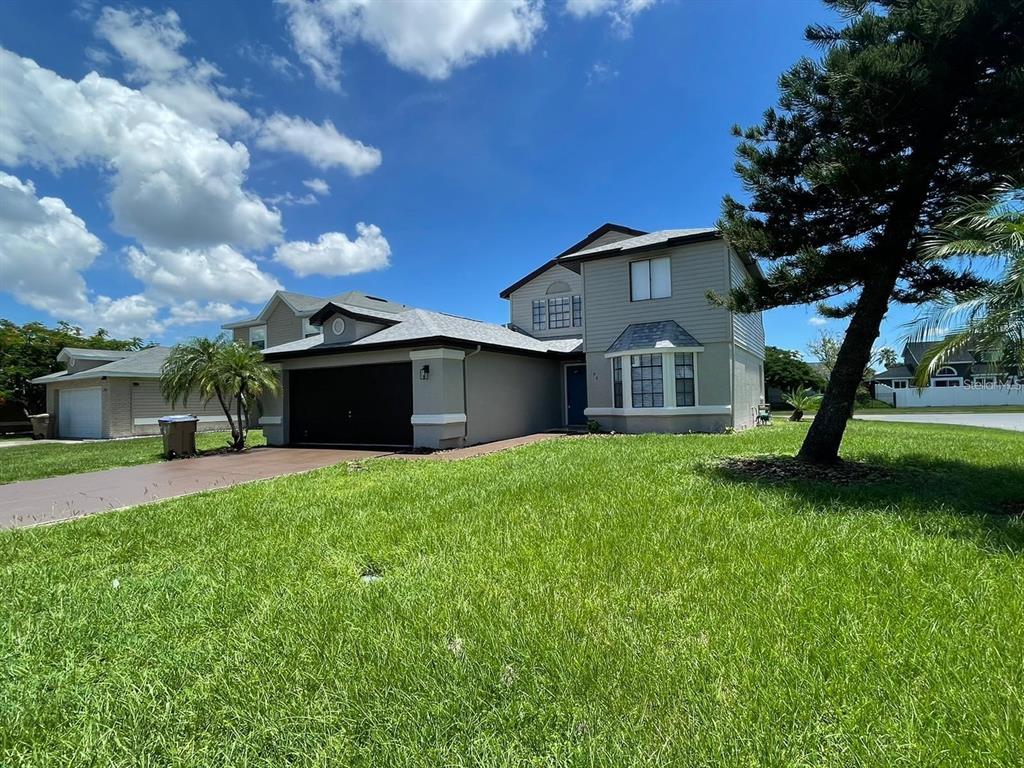 A two-story house with a gray exterior, a dark garage door, and a large front lawn — 198 N LAKE COURT, KISSIMMEE, FL
