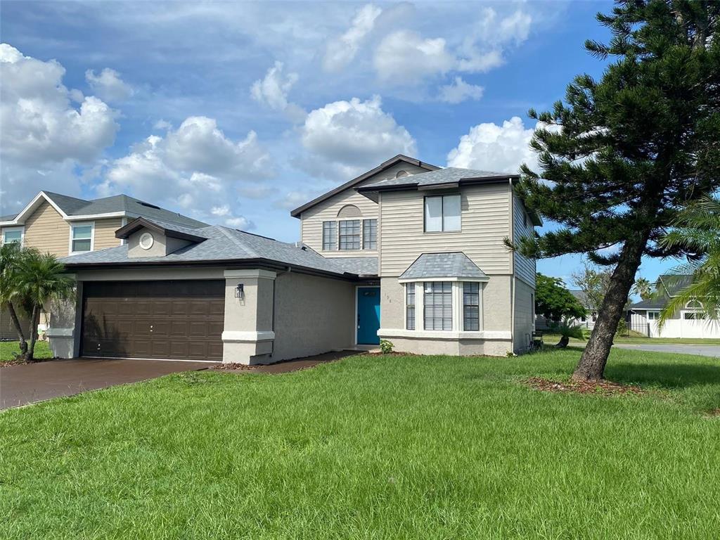 A two-story suburban house with a brown garage, beige siding, and a blue front door — 198 N LAKE COURT, KISSIMMEE, FL