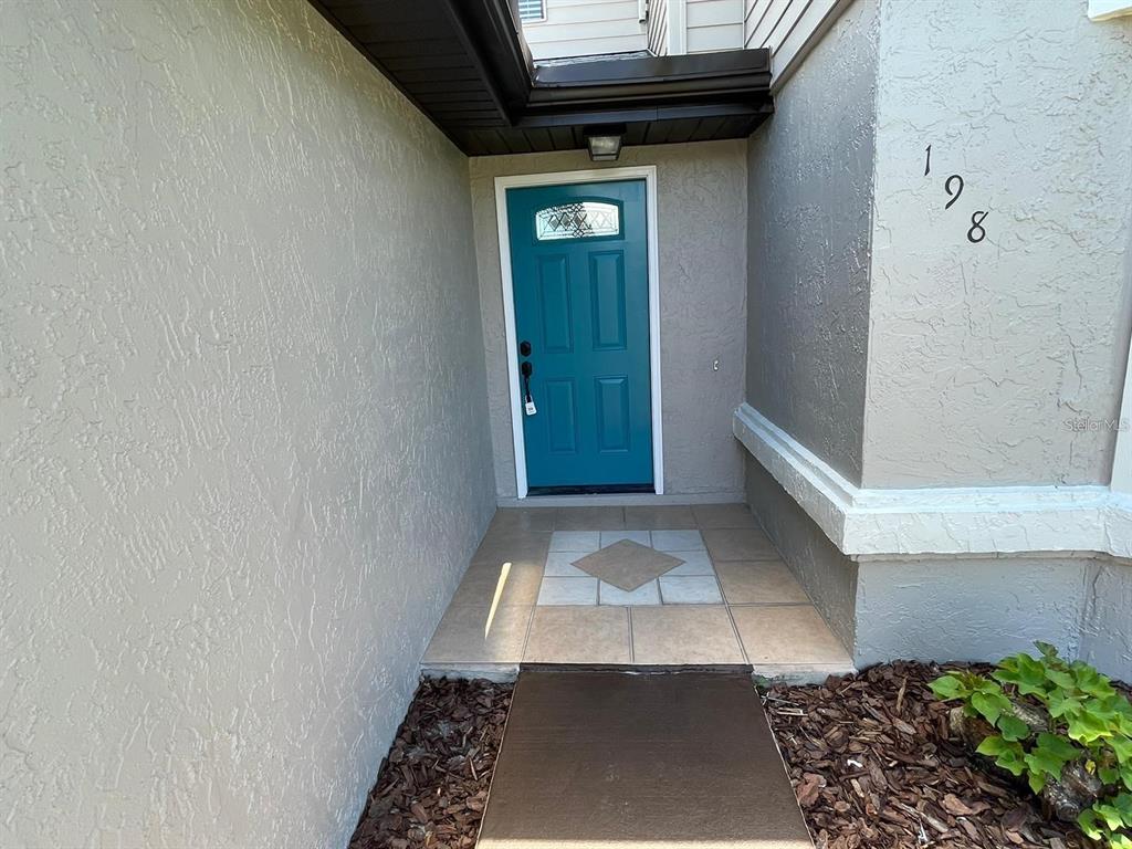 A teal front door with a window is set in a recessed entryway with tile — 198 N LAKE COURT, KISSIMMEE, FL