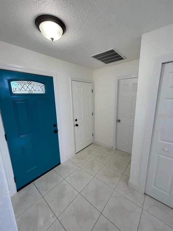 An entryway features a bright blue front door, white interior doors, and light-colored tiled flooring — 198 N LAKE COURT, KISSIMMEE, FL