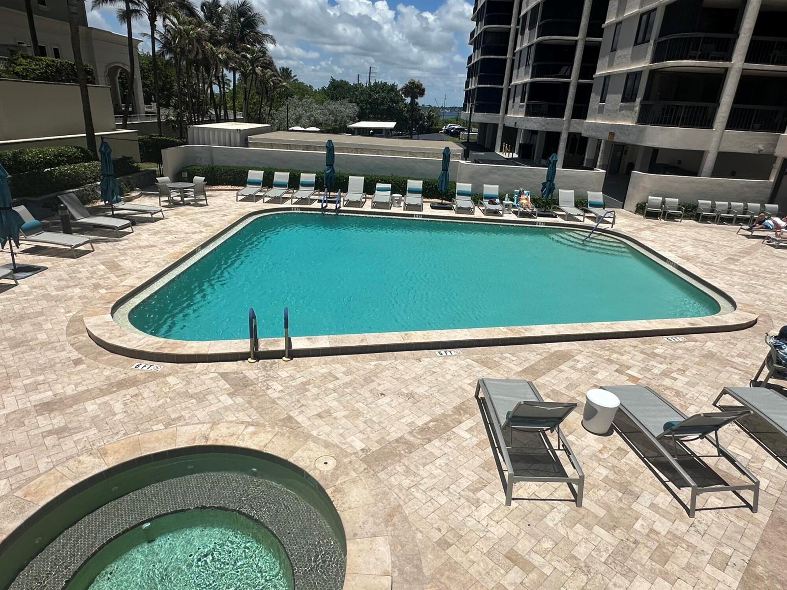 An outdoor swimming pool and hot tub are surrounded by lounge chairs on a stone patio — 5380 N Ocean Drive # 4e, Singer Island FL 33404, SINGER ISLAND, FL